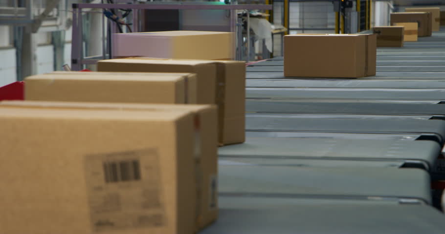 Cardboard Parcels, Boxes, Packages are Transported on an Automated Conveyor Line in a Busy Sorting Center at a Postal Service Warehouse. Concept of Logistics and Shipping Operations
