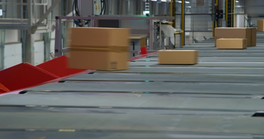 Various Sized Brown Cardboard Packages Move Along a Modern Autonomous Conveyor System in a Large Advanced Distribution Facility. Commercial Logistics and Sorting Center Operating at a Retail Warehouse