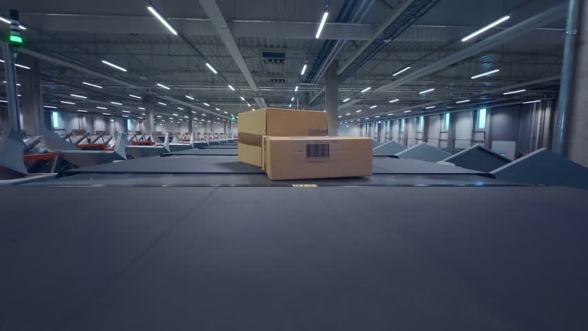 Cardboard Parcel is Transported on a Conveyor Track Through a Large Postal Office or Retail Online Store Logistics Center. POV Footage of Boxes, Mail, Packages Moving in a Distribution Shipping Hub - Powered by Shutterstock - Get 15% off with code: PIKWIZARD15