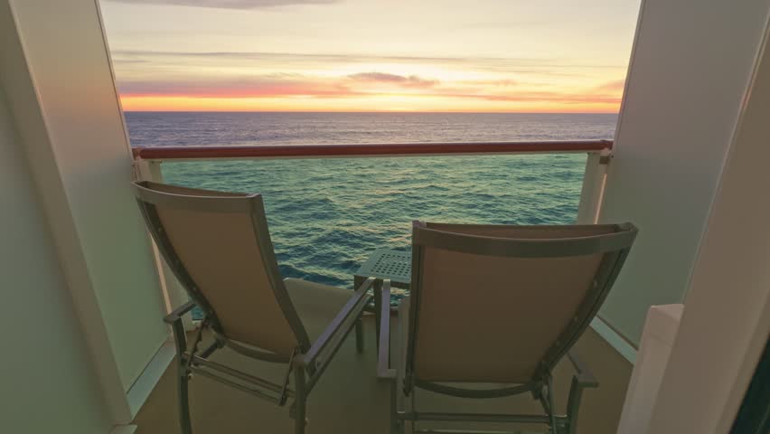 Two chairs and a table on cruise ship cabin balcony looking at the sea, horizon and sunset
