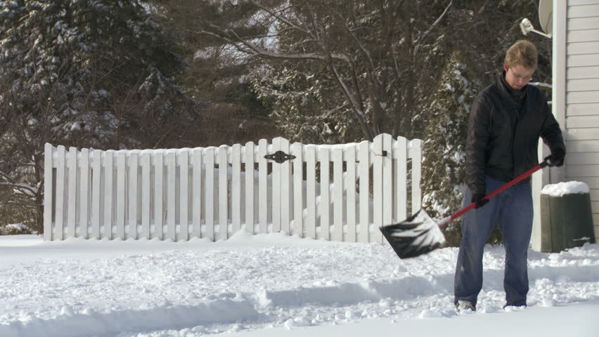 Teenager shoveling snow as fast as he can from a drive in the USA.