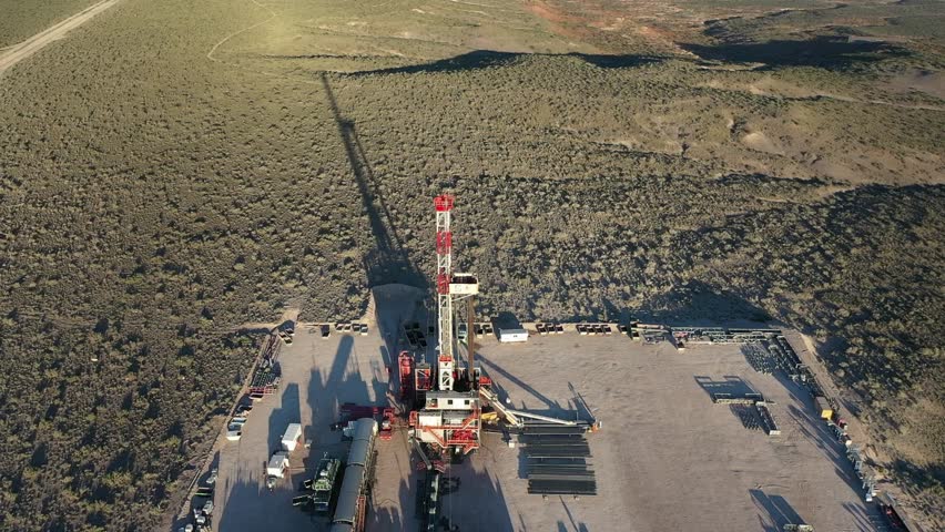 The long shadow of an oil and gas drilling rig is cast over the Patagonian steppe of Vaca Muerta