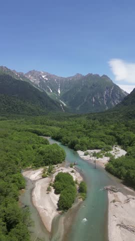Vertical drone video of Kamikochi National Park. Mountains, nature, lush forest, and the Azusa River. Japanese Alps in summer.
