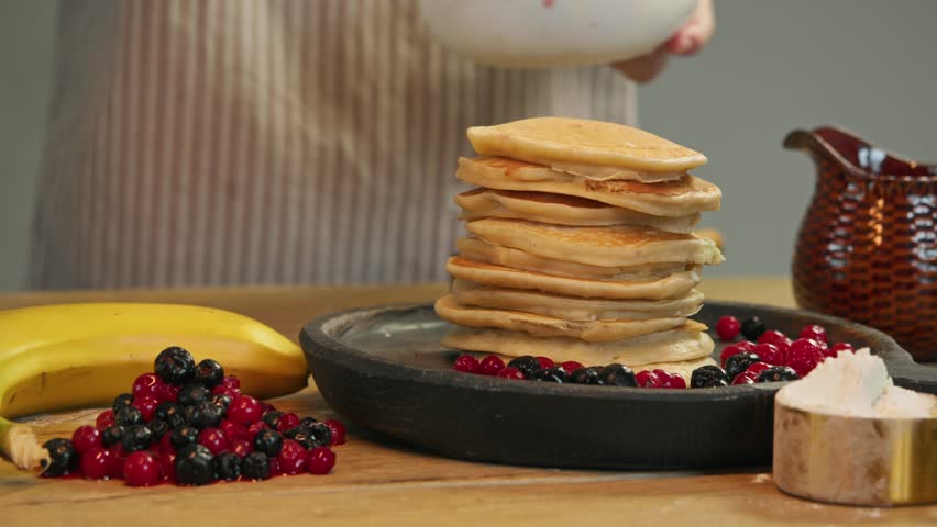 Handful of berries, such as cranberries or currants, are placed on top of delicious stack of hot, fresh pancakes. These berries perfectly complement flavor of traditional breakfast and add touch of