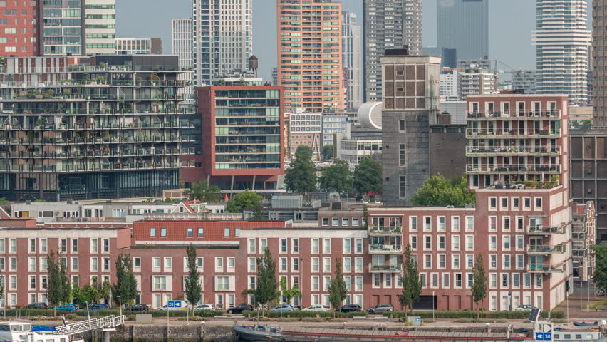 Aerial timelapse of modern buildings in Rotterdam city center, The Netherlands. Towers and skyscrapers in the financial district with warm morning light creating a vibrant skyline. Ships on waterfront