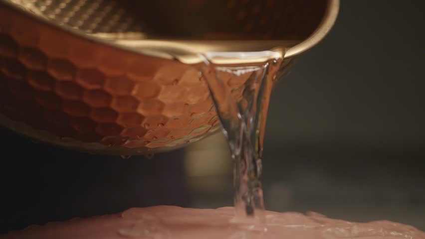 Beautician pouring water from copper ladle during spa treatment