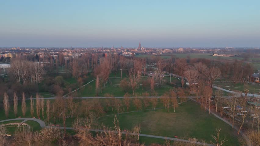 Cremona, Italy February 9th 2025 Aerial view of Cremona, Italy, showcasing the Po river, bare trees, green fields, and urban landscape during a serene sunset