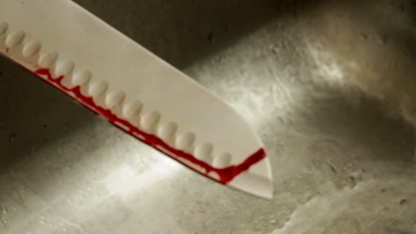 Detail of washing blood off a sharp knife in the kitchen sink. Recorded with