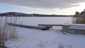 Northern landscape frozen lake snow covered. beautiful crisp and cold ice at amazing winter sunrise. View on north frost fjord or ocean inlet with small dock or pier - Powered by Shutterstock - Get 15% off with code: PIKWIZARD15