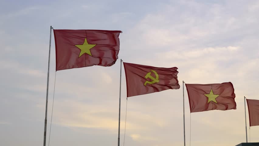 Vietnamese and communist flag waving in slow motion against cloudy sky