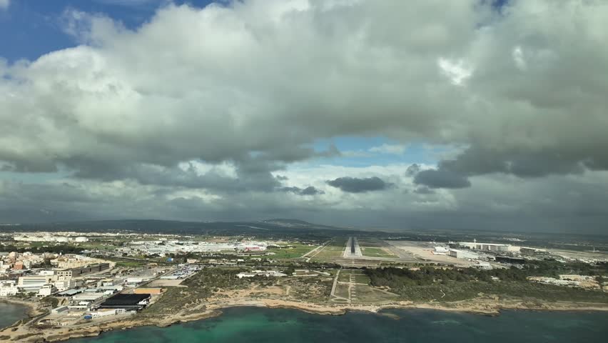 An immersive pilot’s view from the cockpit of a jet airplane approaching to Palma de Mallorca’s airport covered with some cottony clouds.