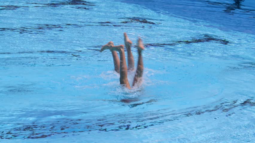 Synchronized or artistic swimming duet performing synchronized legs movement in swimming pool