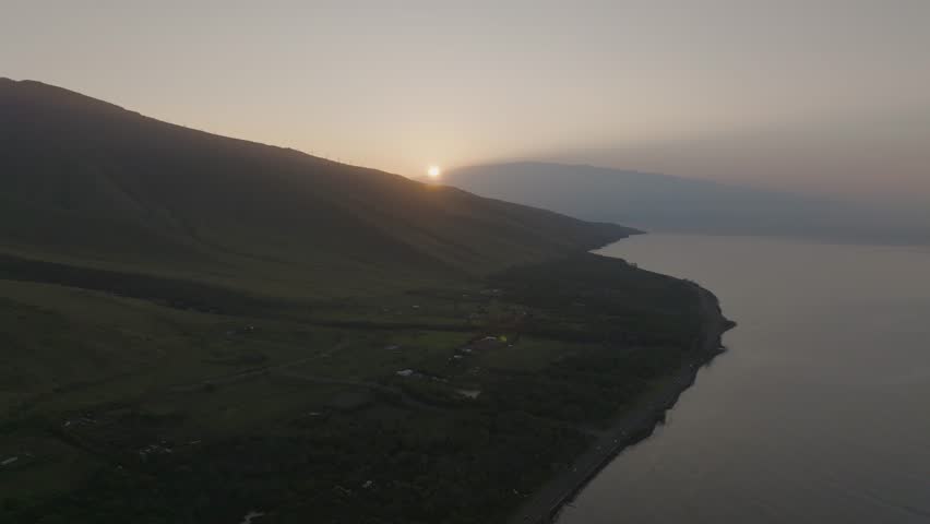 Aerial view of morning sunrise over West Maui, Hawaii Mountains peaks along island coastline landscape - 4K Drone