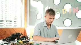 Smart teenager working on laptop and looking at camera at STEM technology class. Caucasian student using computer to analyze data while smiling with confident on table with car model. Edification - Powered by Shutterstock - Get 15% off with code: PIKWIZARD15
