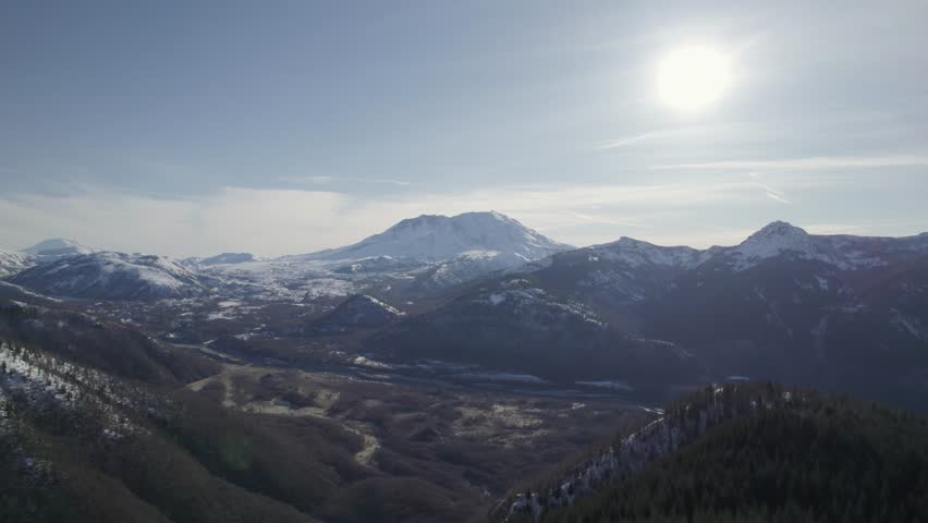 Pull out drone shot of Mount St. Helens in winter with sun shining and snow during the day in Skamania County, Washington, USA