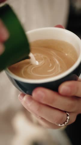 Latte art being created in a coffee cup, close up view