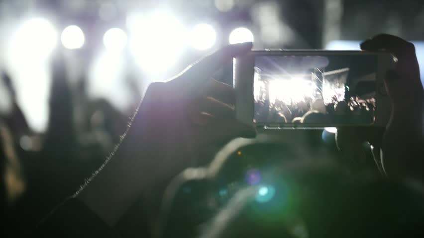 Spectators at the music concert shooting video on the smartphone