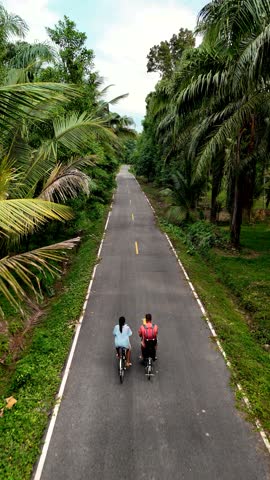 Two cyclists pedal along a remote road surrounded by greenery in Chumphon Thailand. The serene atmosphere invites exploration and connection with nature, showcasing the beauty of this hidden gem.