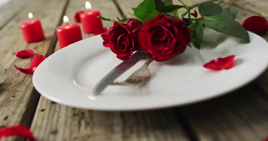 Digital chat icon overlaying red roses and candles on plate. Communication, romance, technology, love, celebration, message