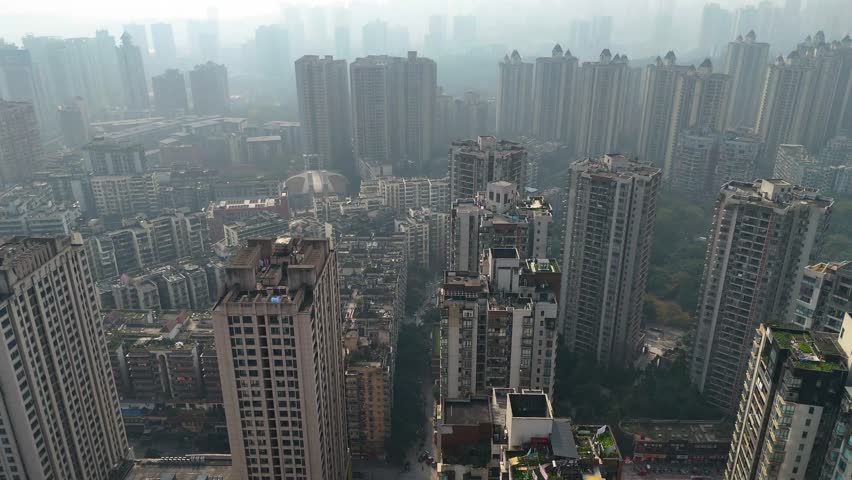 Uprising drone shot of a densely packed residential area in Chongqing, China, showcasing high-rise apartment buildings. Extreme Pollution.