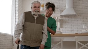 Cheerful African American female caregiver in uniform cheering up handsome elderly man with age-related mobility disability to walk using walking sticks, expressing care , support and happiness. - Powered by Shutterstock - Get 15% off with code: PIKWIZARD15