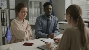 Young diverse couple smiling and answering questions from female consular officer while attending immigration interview at European Union embassy - Powered by Shutterstock - Get 15% off with code: PIKWIZARD15