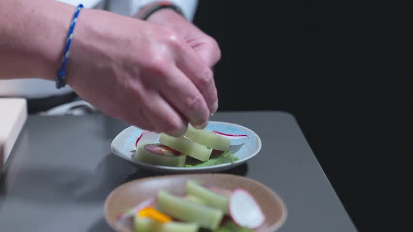 A sliding shot of a chef placing decorative touches on sushi rolls, showcasing sushi preparation and presentation. Perfect for highlighting Japanese cuisine and food styling in culinary settings.