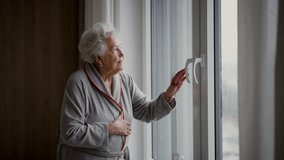 Beautiful old woman looking out of window, expecting a visitor. - Powered by Shutterstock - Get 15% off with code: PIKWIZARD15