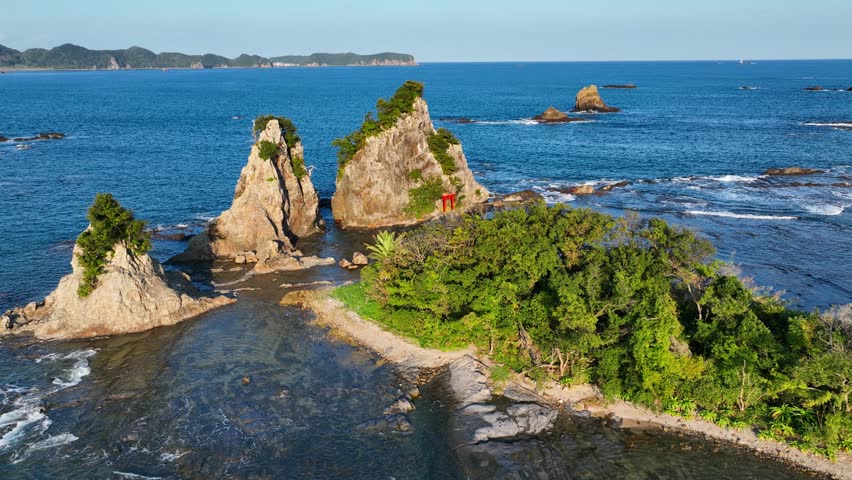Japanese islands, travel in Japan, Cliffs in the ocean off the coast of Japan with traditional red tori gate, aerial view of Japanese coastline. High quality 4k footage
