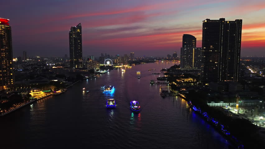 Aerial view of illuminated skyscrapers in Bangkok city and Chao Phraya River in night time, 4k