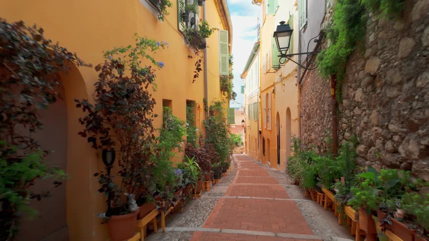 POV shot while walking through narrow street of Menton, a resort town on the French Riviera, France. The colourful old town of Menton in summer on the Cote dAzur.