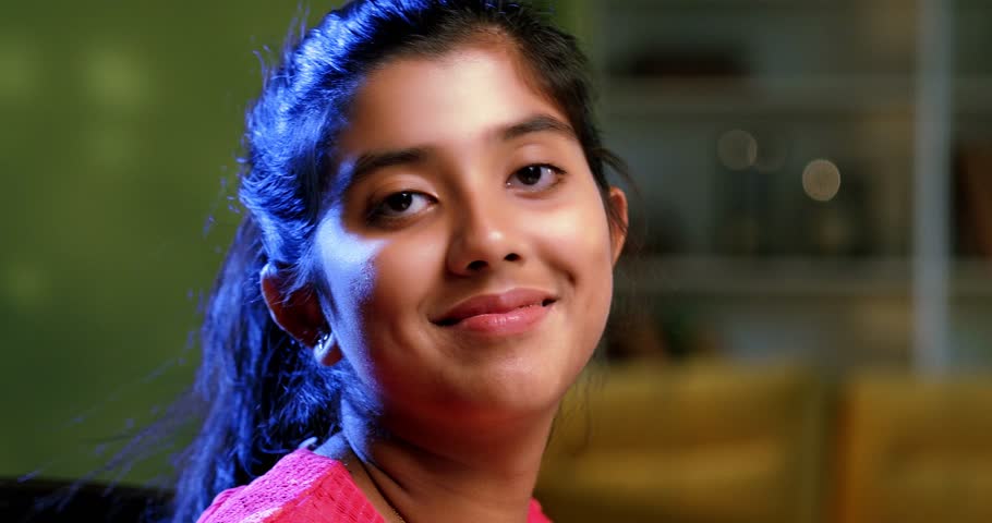 Indian Asian teenage beautiful playful girl sitting in a cozy lavish home, studying from a book, creatively making it a roof over her head in fun, expressing joy, innocence, a lighthearted approach