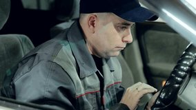 Professional automotive technician sitting in car driver seat at night, focusing intently while browsing smartphone during work break, displaying concentrated digital engagement - Powered by Shutterstock - Get 15% off with code: PIKWIZARD15