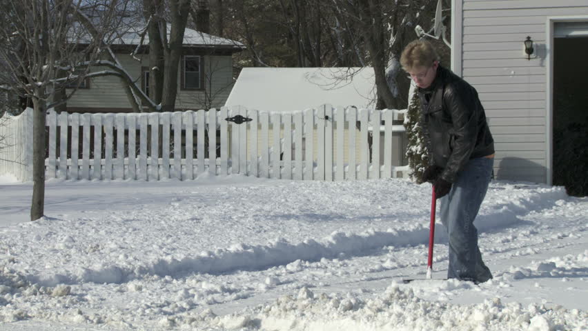 Digging out a snow-covered driveway in the Mid West, USA. Full length shot.