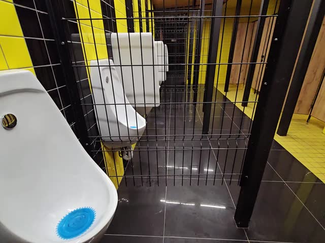 Row of urinals with a blue lid on the left urinal. The urinals are in a yellow room