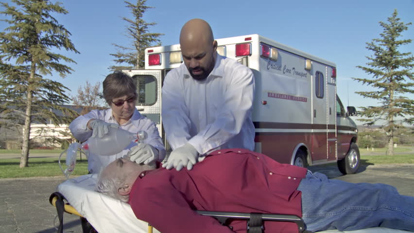 Two paramedics perform resuscitation on an unconscious male patient using a