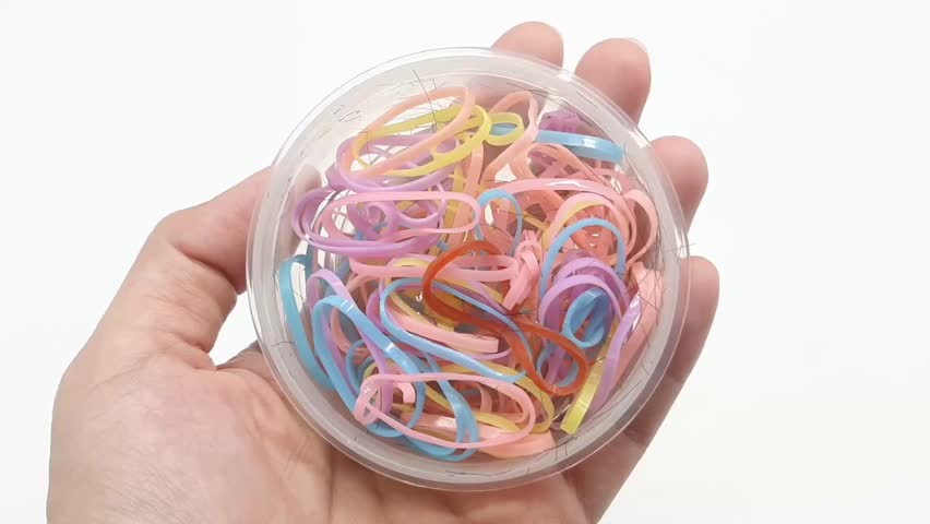 Hand Holding a Clear Round Plastic Box with Used Colorful Hair Ties – Hair Accessory Storage