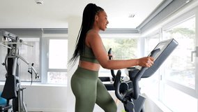 Black businesswoman exercising on elliptical cross trainer in hotel fitness room during business trip - Powered by Shutterstock - Get 15% off with code: PIKWIZARD15