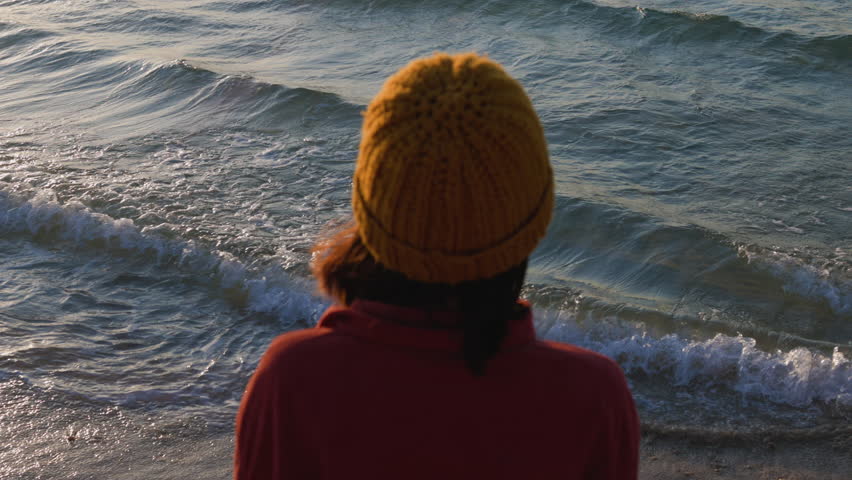 Woman looking at ocean at sunset thinking about life. Back view. Stylish girl looking at ocean, Girl enjoying vacation and travel.