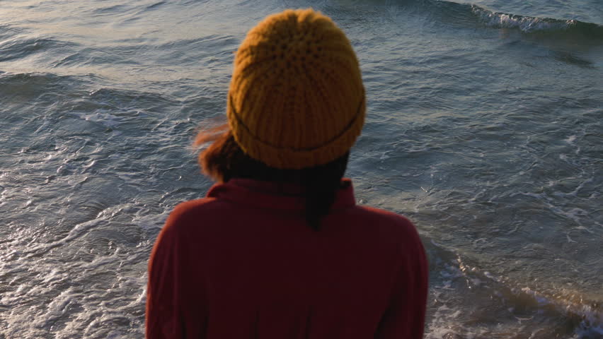 Woman looking at ocean at sunset thinking about life. Back view. Stylish girl looking at ocean, Girl enjoying vacation and travel.