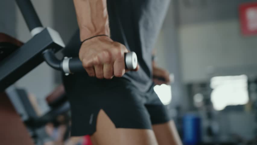 A determined man working out on dip bars in a modern gym, focusing on strength and fitness training. The gym environment is visibly equipped with contemporary facilities. Focused Man Exercising