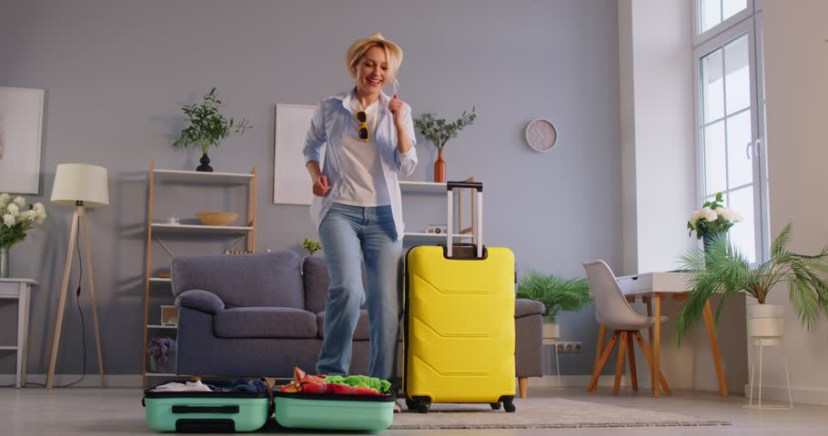 Positive woman packing a suitcase and preparing for a summer vacation or trip at home. Excitement and celebration of travel, holiday preparation, and the joy of planning a getaway.