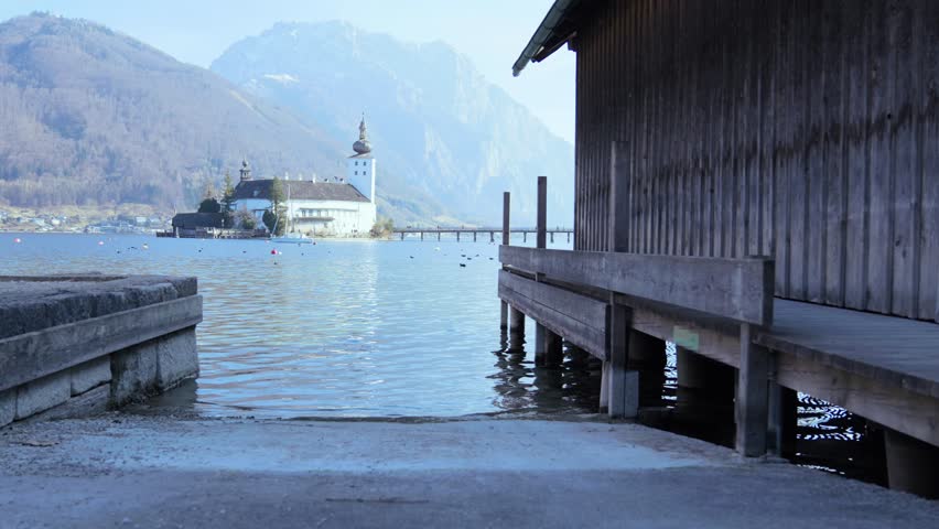Seeschloss Gmunden centered, framed by wooden structures. Scenic view. Architectural lake scene.
