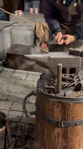 A young blacksmith forges a horseshoe in the Middle Ages