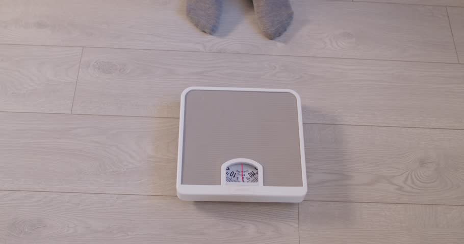 Top close up view of person standing on scales on floor, measuring weight, checking progress of weight loss. Overweight, dieting, healthy lifestyle, examining fat with weighing and slimming concept.