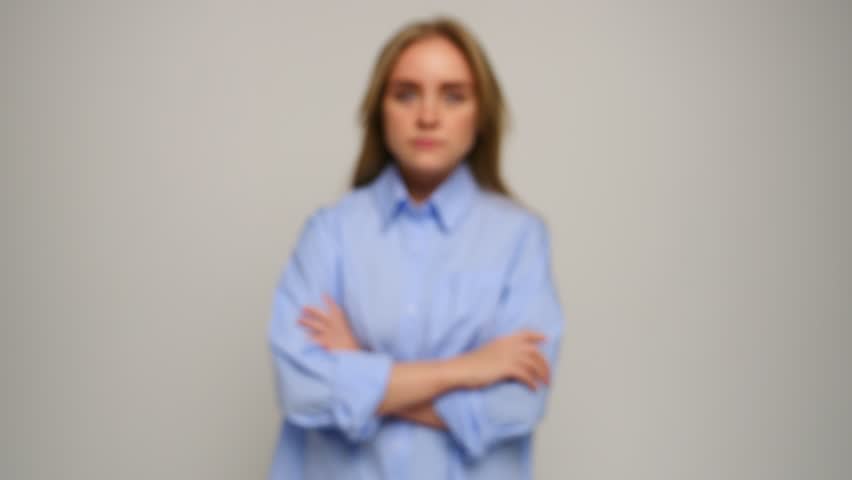 Young woman poses with crossed arms, displaying confidence while dressed in formal attire.