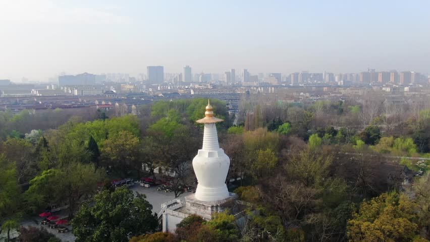 Aerial footage of the iconic White Pagoda at Slender West Lake, showcasing its historical architecture and its prominent role as a landmark in the scenic area.

