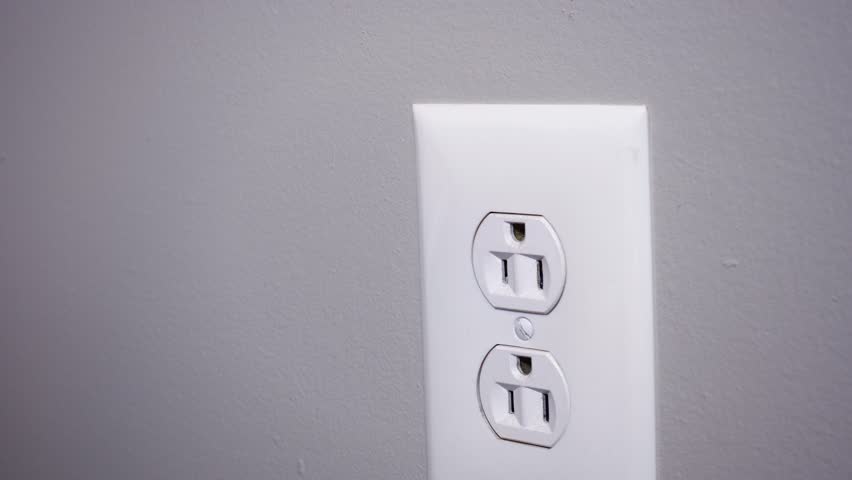 A close up shot of a man plugging in a typical WiFi extender into a household wall outlet. With simulated hotspot radio waves emanating from the device.  	
