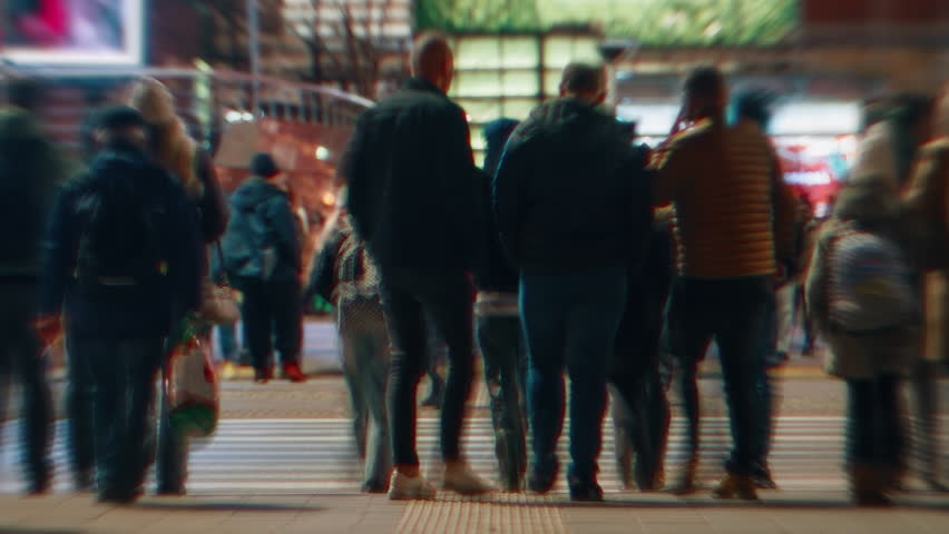Time-lapse unrecognizable people crowd crossing city street, busy crossroad intersection, blurry pedestrians walking crosswalk in evening. Rush hour many people walk, blurred fast motion at night