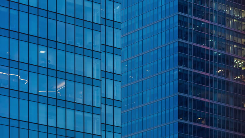 Day to night transition office windows lights time-lapse, modern high-rise skyscrapers, financial district tall glass buildings in downtown looking up wide angle shot, people working late evening